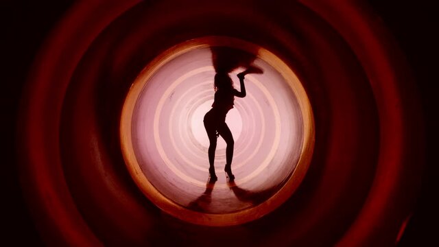 A silhouette of beautiful sexy girl , woman dancing inside circle tube . Against colored & gray background . Real decoration . None computer graphics . Shot on Arri Alexa Cinema Camera in 4K .