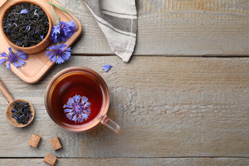Flat lay composition with tea and cornflowers on wooden table. Space for text