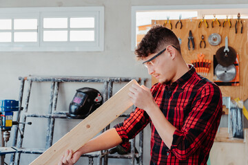 young caucasian carpenter cutting wooden board	