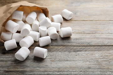 Fototapeta na wymiar Delicious puffy marshmallows on wooden table, closeup. Space for text