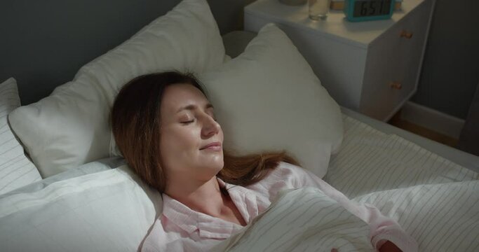 Close up. View from top of Caucasian happy pretty woman sleeping in bed, waking up in good mood in morning with smile on face. Beautiful female wake up in bedroom at home, sweet dreams concept