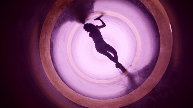 A silhouette of beautiful sexy girl , woman dancing inside circle tube . Against colored & gray background . Real decoration . None computer graphics . Shot on Arri Alexa Cinema Camera in 4K .
