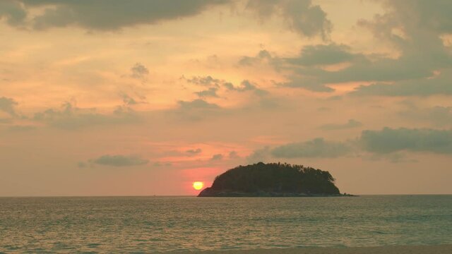 scenery yellow sun going down to the sea..beautiful moving cloud in sweet sky at sunset in Kata beach Phuket Thailand.4k stock footage video in travel concept.