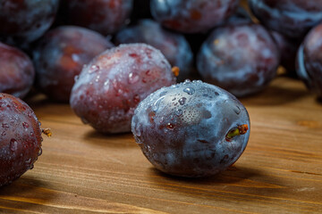 fresh plums on a plate on wooden table