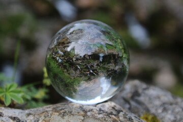 Glaskugel mit Reflektion von einem Wasserfall im Hintergrund 