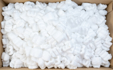 Fototapeta na wymiar Top view of white polystyrene foam in parcel box. Polystyrene foam cushioning material for packaging, A cardboard box with packing foam pellets.