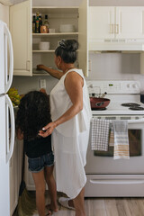 Filipino senior grandmother in kitchen teaching black filipino mixed grand daughter to cook