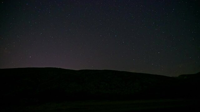 Timelapse of stars in the mountains with lights, planetracks and meteors, 4K.