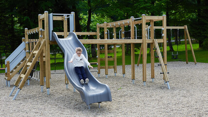 Little girl on a playground. Child playing outdoors in summer. Kids play on school yard.
