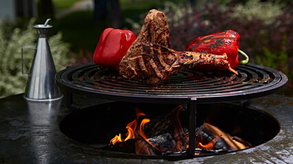 Tomahawk rib beef steak and T-bone on hot black grill.