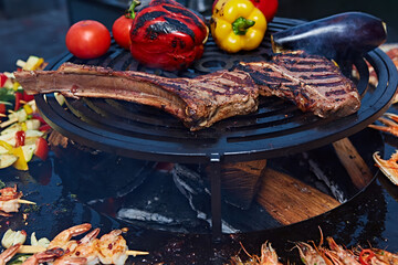 Tomahawk rib beef steak and T-bone on hot black grill.