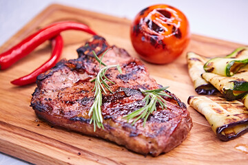 Grilled T-Bone Steak on serving board on wooden background