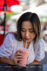 Young Petite Asian Woman Drinking a Strawberry and Banana Smoothie