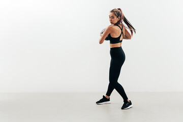 Obraz premium Young muscular woman doing exercises with a medicine ball against a white wall