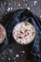Layered carrot cake dessert in a plastic cup on a wooden table with coconut flakes and black kitchen towel. Flatlay. 