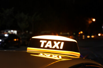 Taxi car with yellow sign outdoors at night