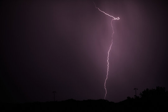 Gewitter. Blitz in der Nacht erhellt Wolken, Silhouette einer Stadt hebt sich ab.