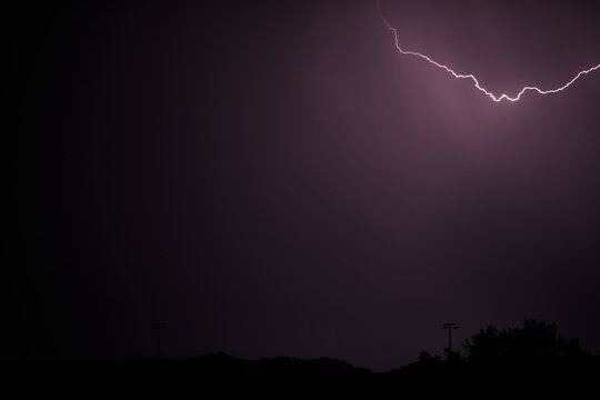Gewitter. Blitz in der Nacht erhellt Wolken, Silhouette einer Stadt hebt sich ab.