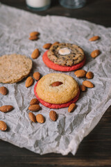 Various cookies surrounded by almonds  on baking parchment and wooden table