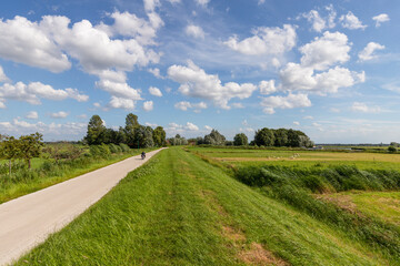 Fototapeta na wymiar Clouds, a blue sky and a lot of wind above the rural polder landscape in the Netherlands.