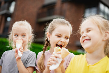 Siblings Enjoying Ice Cream Together. Three little girls eats ice cream outdoors in park