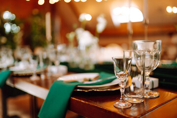 Banquet Seating Table in the restaurant in emerald color, the preparation before the banquet. The work of professional florists. Wedding, birthday, party, event concept.