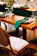 Banquet Seating Table in the restaurant in emerald color, the preparation before the banquet. The work of professional florists. Wedding, birthday, party, event concept.