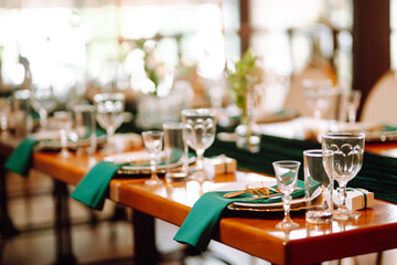 Banquet Seating Table in the restaurant in emerald color, the preparation before the banquet. The work of professional florists. Wedding, birthday, party, event concept.