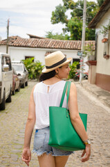 Fototapeta premium Tourist woman walking in the street in a rustic village in summer wearing in white and green