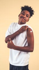 African American teenager showing COVID-19 vaccine bandage merrily in concept of coronavirus...