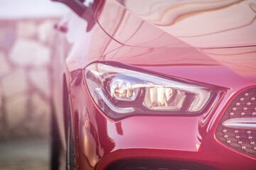 headlight and radiator grille of a beautiful red car with pink tint