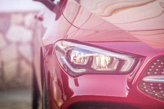 headlight and radiator grille of a beautiful red car with pink tint