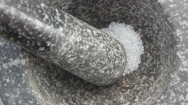 Close-up of brown sugar and peppers falling into the grey stone mortar