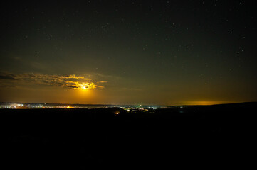 Moonlit summer night near a village in a field