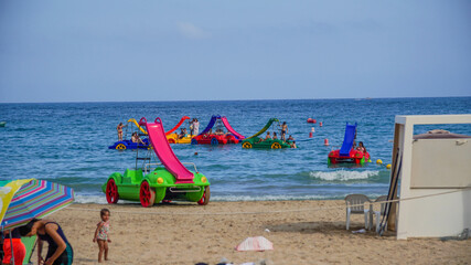 Patines de mar a pedales de vivos colores con tobogan delante de la playa en Alicante - obrazy, fototapety, plakaty