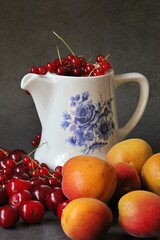 scattered cherries, apricots and red currants, green knife, colorful fruit, jug filled with currants