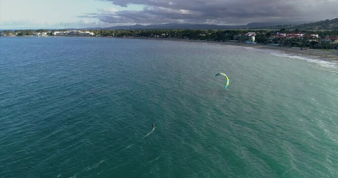 The drone follows a kiter on a hydrofoil. The athlete rides the water very quickly on the board. Water sports. Drone view of the blue daguna in the sunset light. Kiter rides in the lagoon near the coa