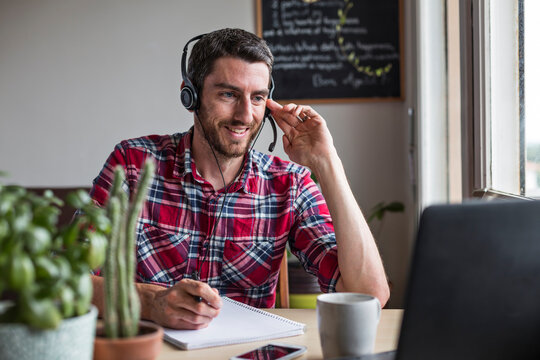 Man working from home in conference call with colleagues using headset
