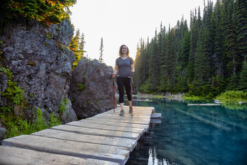 Adventurous White Caucasin Adult Woman Hiking on a trail in Canadian Nature. Sunset Sky. Garibaldi...