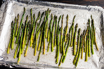 Fototapeta premium Roasted Asparagus Spears on a Foil Lined Sheet Pan: Roasted asparagus seasoned with extra virgin olive oil, kosher salt, and black pepper