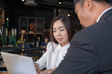 Asian businessman and businesswoman in the formal suits are discussing work in then modern office  place with high technology laptop