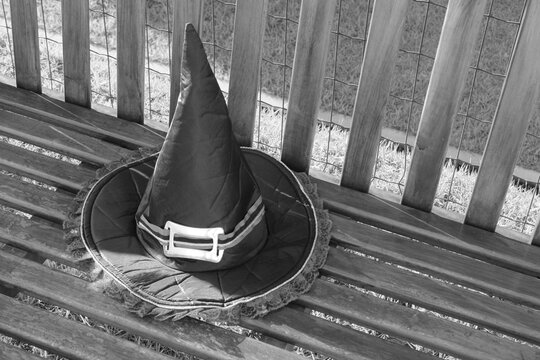 Chap&eacute;u de bruxa preto sobre um banco de madeira