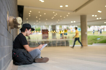 young student writing ideas, sitting outdoors