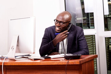 adult business man talking on mobile phone in office smiling.