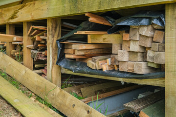 Wood stacked and stored in a garden under a shed