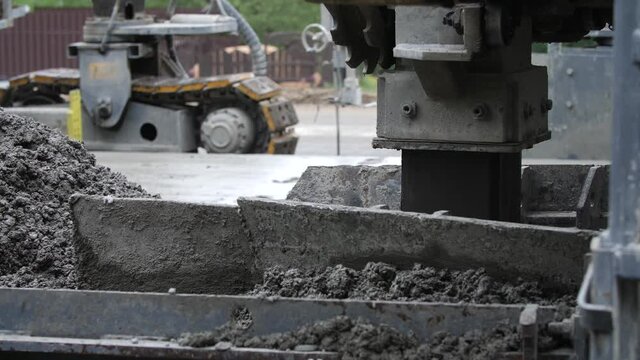Detailed view of road paver finisher or heavy construction machine spreading layer of asphalt concrete over roadway base to prepare screed. Concept of operation of highway or motorway paving process.