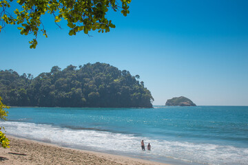 Paradisiac landscape of a beach in the tropical pacific on a couple in couple with white sand and blue sky in the National Park. Manuel Antonio in Costa Rica