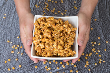 Manos sosteniendo unas palomitas con caramelo