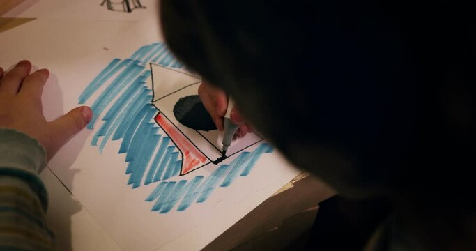 Cinematic close-up, hand of little boy child drawing space rocket on paper at table dreaming about becoming astronaut.