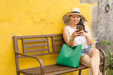 Portrait of young woman painting in a canvas over a easel in a sea landscape wearing a blue dress and hat